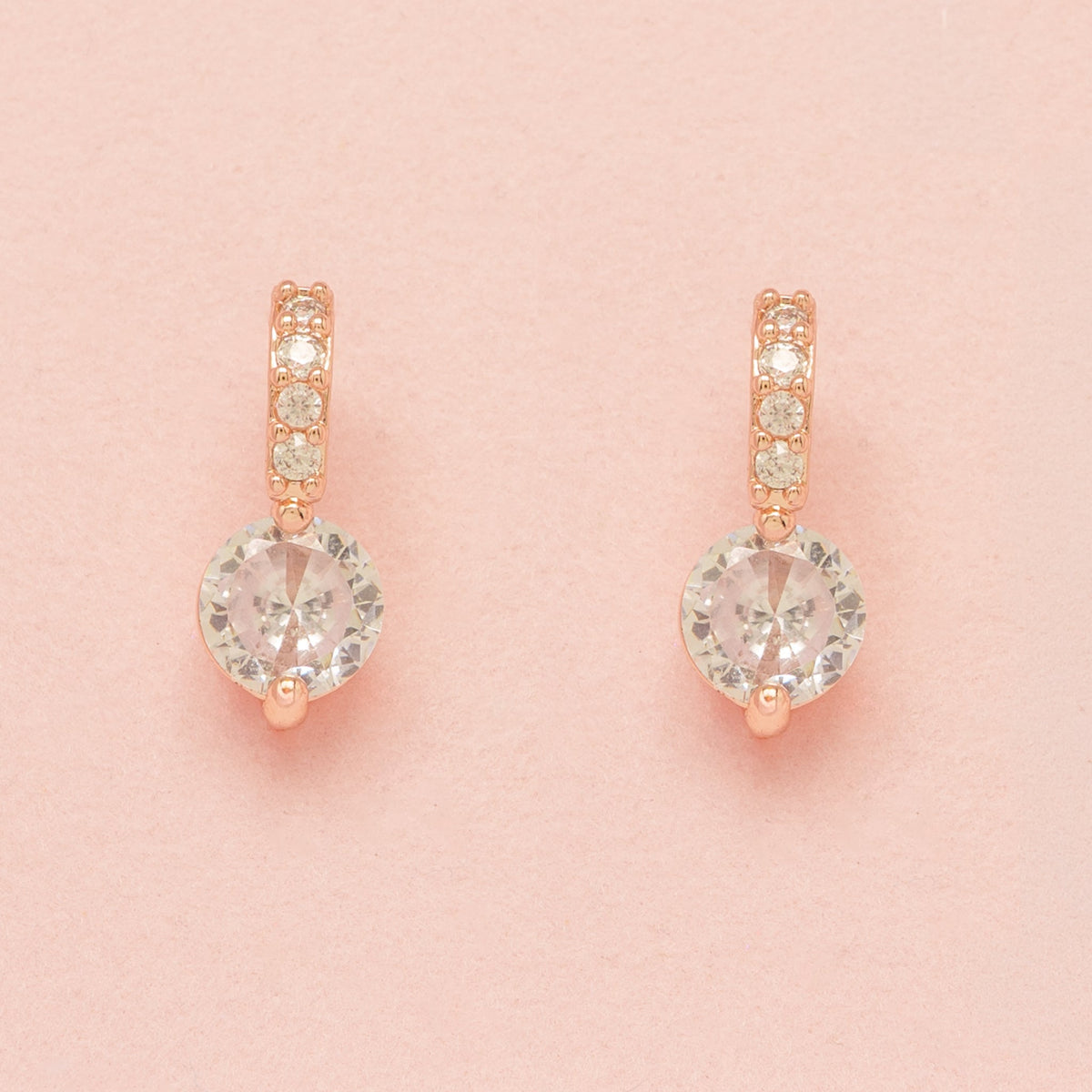 Elegant Wishes rose gold crystal earrings on a pink background