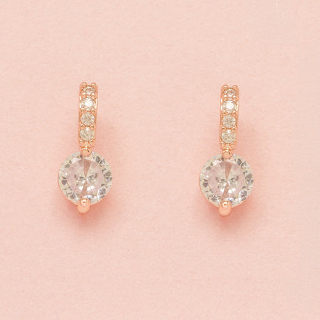 Elegant Wishes rose gold crystal earrings on a pink background